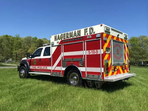 Exterior view of small fire truck showing cab, body compartments, and wheel/tire area.