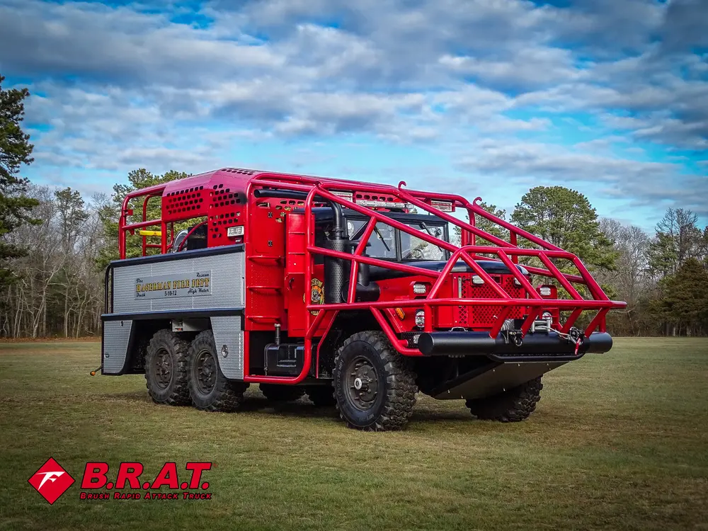Exterior view of small fire truck showing cab, body compartments, and wheel/tire area.