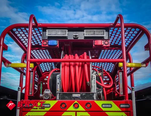 Exterior view of small fire truck showing cab, body compartments, and wheel/tire area.