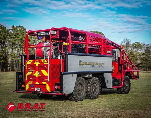 Exterior view of small fire truck showing cab, body compartments, and wheel/tire area.