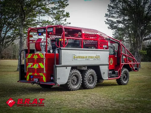 Exterior view of small fire truck showing cab, body compartments, and wheel/tire area.