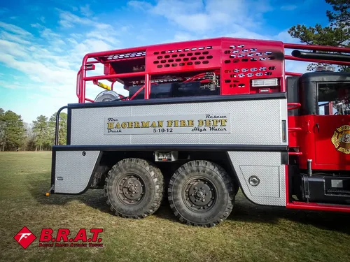 Exterior view of small fire truck showing cab, body compartments, and wheel/tire area.
