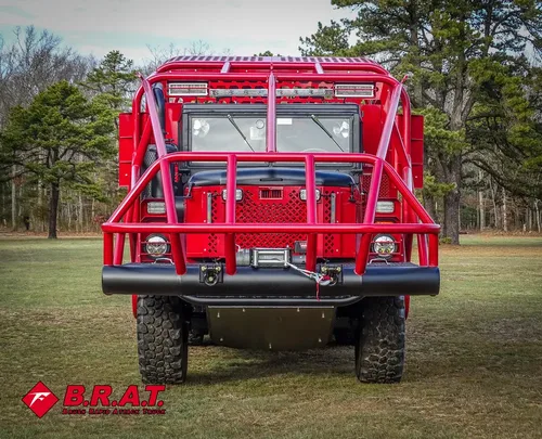 Exterior view of small fire truck showing cab, body compartments, and wheel/tire area.