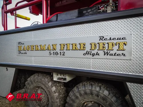 Exterior view of small fire truck showing cab, body compartments, and wheel/tire area.