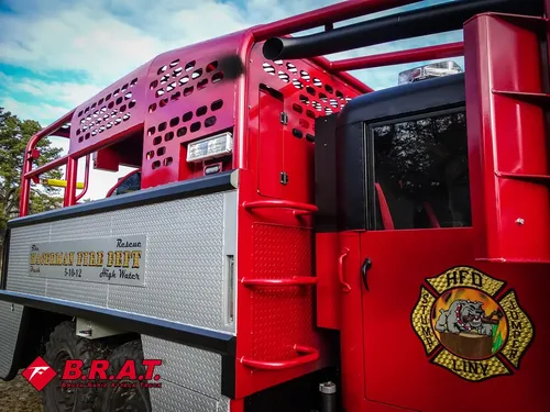 Exterior view of small fire truck showing cab, body compartments, and wheel/tire area.