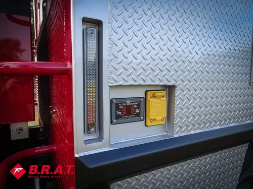 Exterior view of small fire truck showing cab, body compartments, and wheel/tire area.