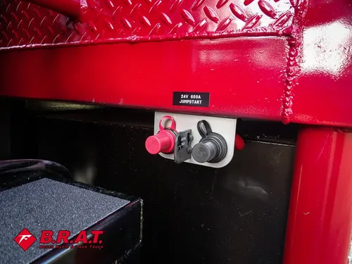 Exterior view of small fire truck showing cab, body compartments, and wheel/tire area.