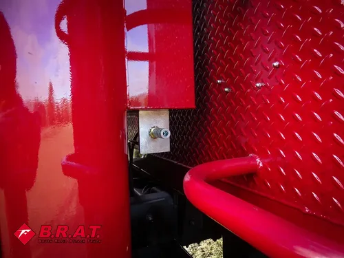 Exterior view of small fire truck showing cab, body compartments, and wheel/tire area.