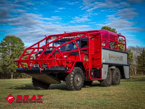 Exterior view of small fire truck showing cab, body compartments, and wheel/tire area.