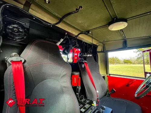 Exterior view of small fire truck showing cab, body compartments, and wheel/tire area.