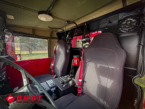 Exterior view of small fire truck showing cab, body compartments, and wheel/tire area.