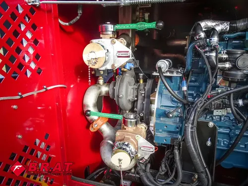 Exterior view of small fire truck showing cab, body compartments, and wheel/tire area.