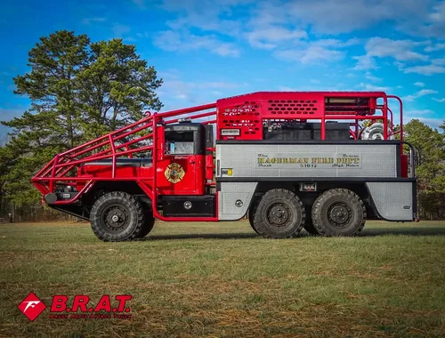 Exterior view of small fire truck showing cab, body compartments, and wheel/tire area.