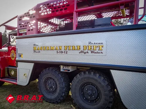 Exterior view of small fire truck showing cab, body compartments, and wheel/tire area.