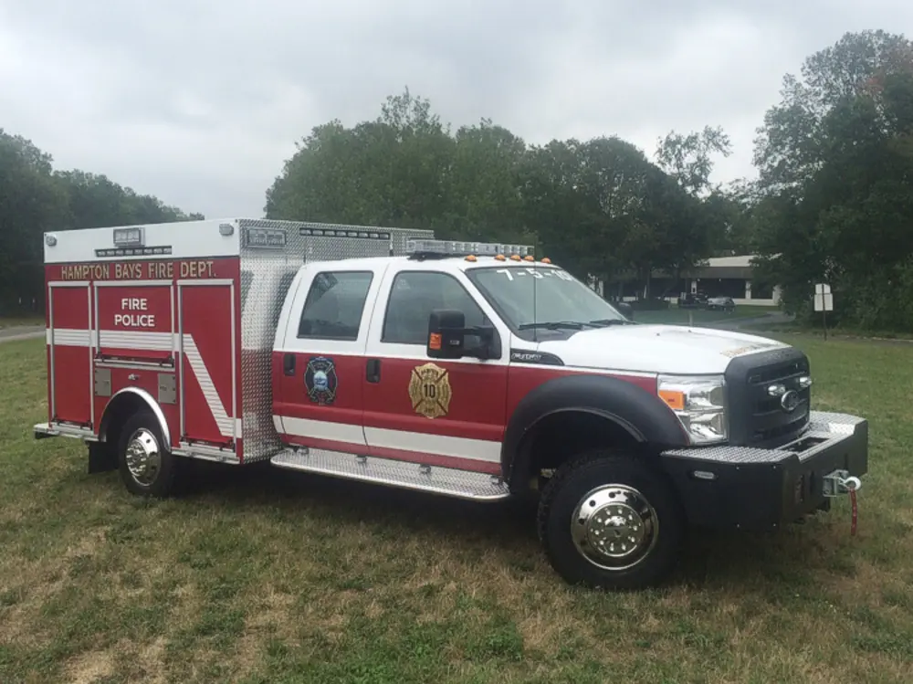 Exterior view of small fire truck showing cab, body compartments, and wheel/tire area.