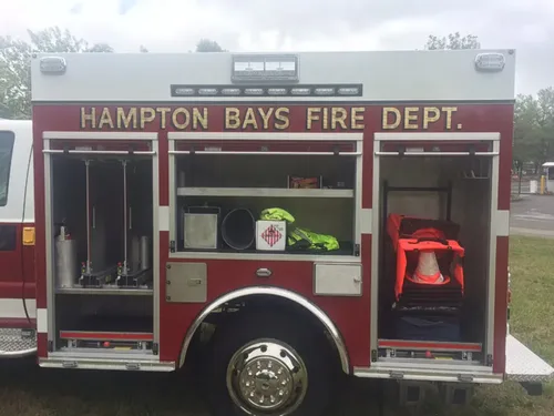 Exterior view of small fire truck showing cab, body compartments, and wheel/tire area.