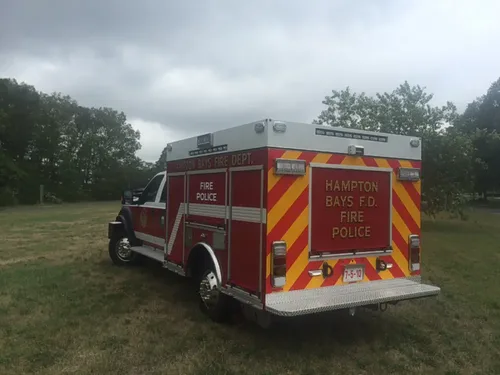 Exterior view of small fire truck showing cab, body compartments, and wheel/tire area.