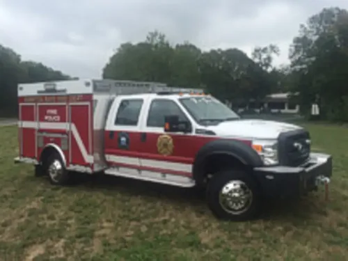 Exterior view of small fire truck showing cab, body compartments, and wheel/tire area.
