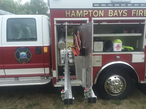 Exterior view of small fire truck showing cab, body compartments, and wheel/tire area.