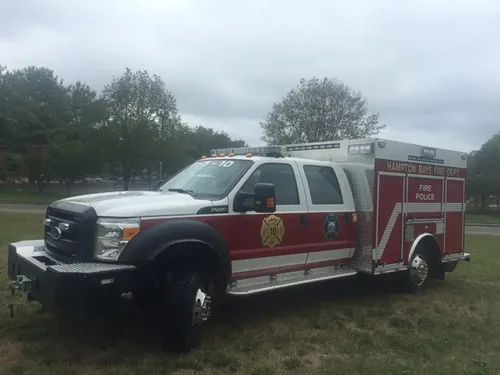 Exterior view of small fire truck showing cab, body compartments, and wheel/tire area.