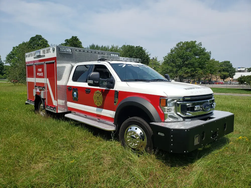 Exterior view of small fire truck showing cab, body compartments, and wheel/tire area.