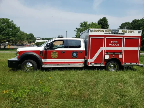 Exterior view of small fire truck showing cab, body compartments, and wheel/tire area.