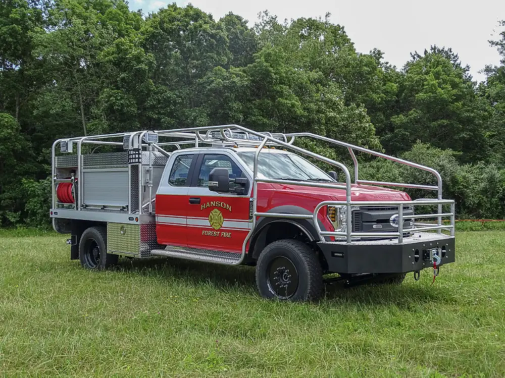 Exterior view of small fire truck showing cab, body compartments, and wheel/tire area.