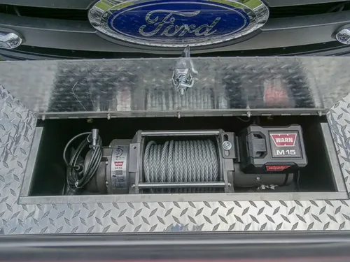 Exterior view of small fire truck showing cab, body compartments, and wheel/tire area.