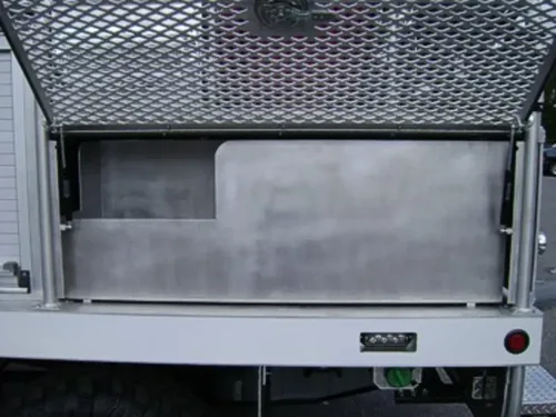 Exterior view of small fire truck showing cab, body compartments, and wheel/tire area.