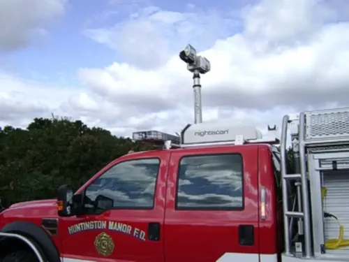 Exterior view of small fire truck showing cab, body compartments, and wheel/tire area.