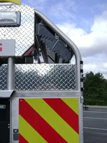 Exterior view of small fire truck showing cab, body compartments, and wheel/tire area.