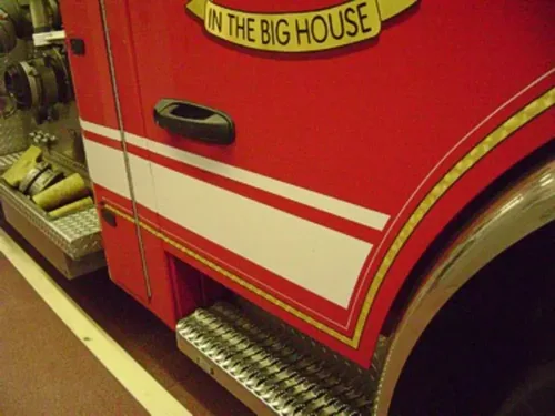 Exterior view of small fire truck showing cab, body compartments, and wheel/tire area.