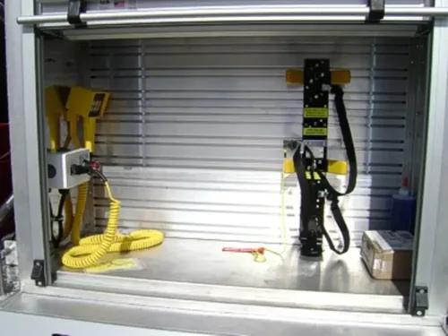 Exterior view of small fire truck showing cab, body compartments, and wheel/tire area.