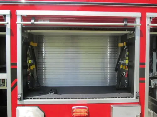 Exterior view of small fire truck showing cab, body compartments, and wheel/tire area.
