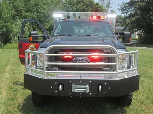 Exterior view of small fire truck showing cab, body compartments, and wheel/tire area.