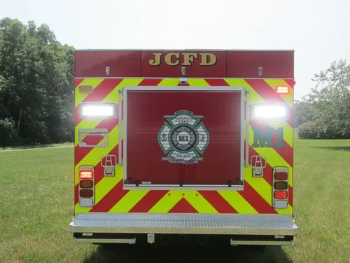 Exterior view of small fire truck showing cab, body compartments, and wheel/tire area.