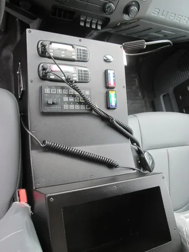 Exterior view of small fire truck showing cab, body compartments, and wheel/tire area.