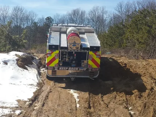 Exterior view of small fire truck showing cab, body compartments, and wheel/tire area.