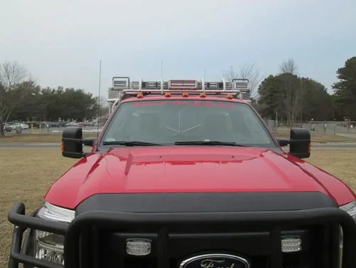 Exterior view of small fire truck showing cab, body compartments, and wheel/tire area.