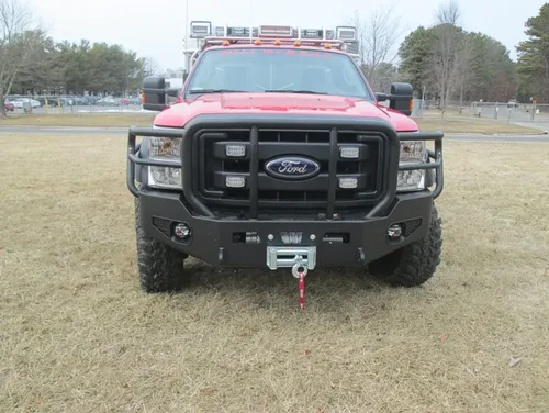 Exterior view of small fire truck showing cab, body compartments, and wheel/tire area.