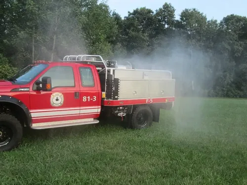 Exterior view of small fire truck showing cab, body compartments, and wheel/tire area.