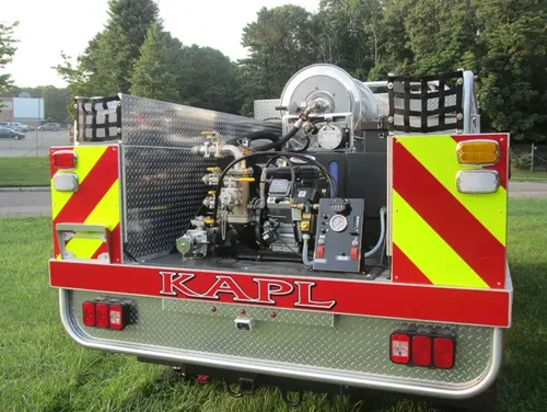 Exterior view of small fire truck showing cab, body compartments, and wheel/tire area.
