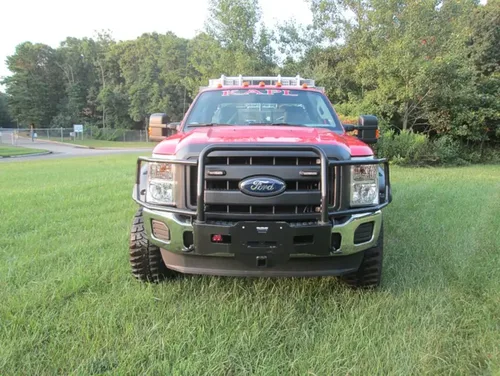 Exterior view of small fire truck showing cab, body compartments, and wheel/tire area.