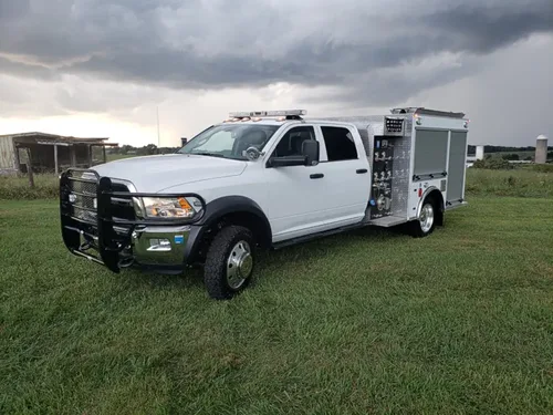 Exterior view of small fire truck showing cab, body compartments, and wheel/tire area.