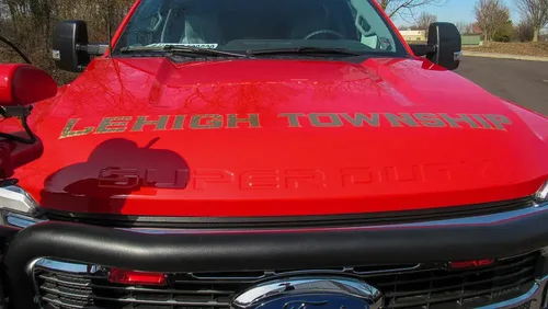 Exterior view of small fire truck showing cab, body compartments, and wheel/tire area.