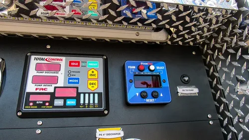 Exterior view of small fire truck showing cab, body compartments, and wheel/tire area.