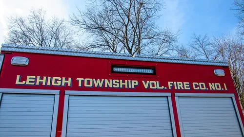 Exterior view of small fire truck showing cab, body compartments, and wheel/tire area.