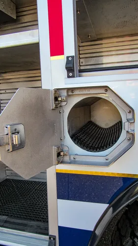 Exterior view of small fire truck showing cab, body compartments, and wheel/tire area.