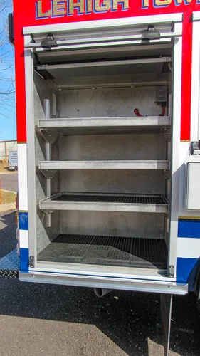 Exterior view of small fire truck showing cab, body compartments, and wheel/tire area.