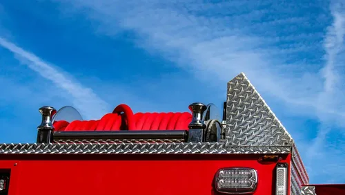 Exterior view of small fire truck showing cab, body compartments, and wheel/tire area.